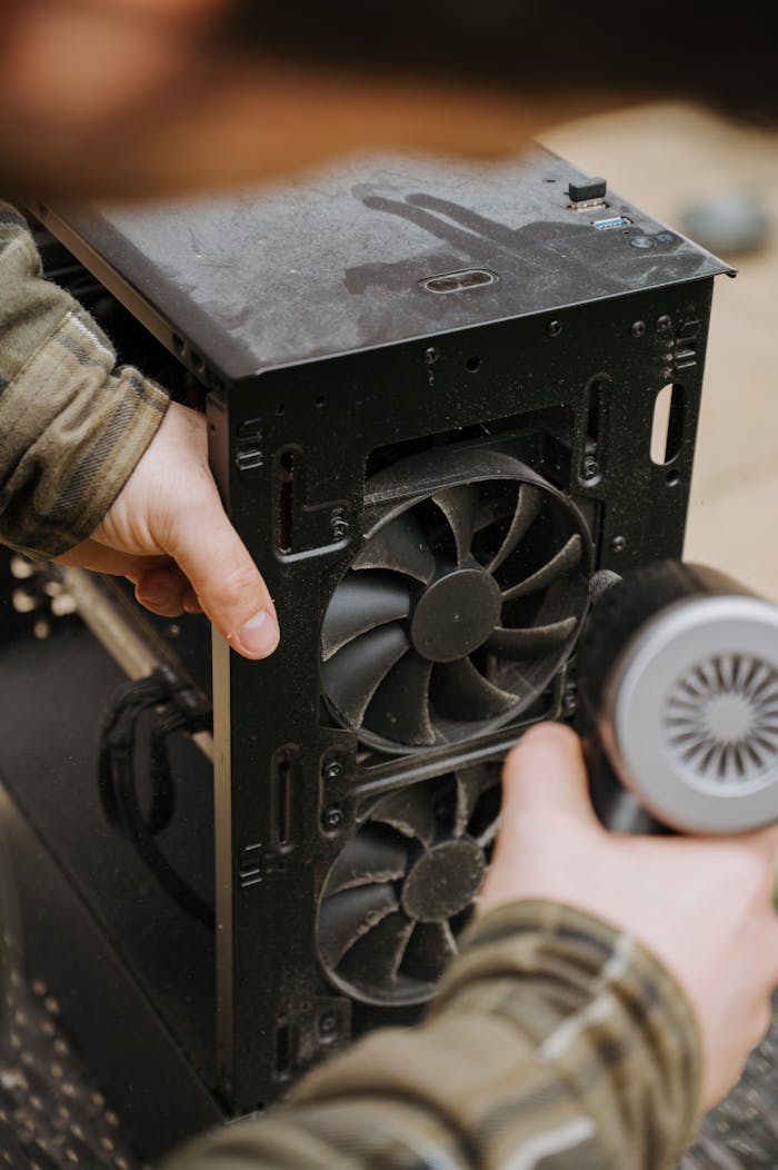 why-choose-us Hands cleaning dust from a computer fan using an electric air duster for maintenance.