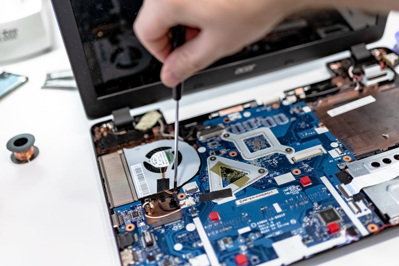 creative-01 Hand repairing a laptop motherboard with a screwdriver, highlighting tech maintenance.