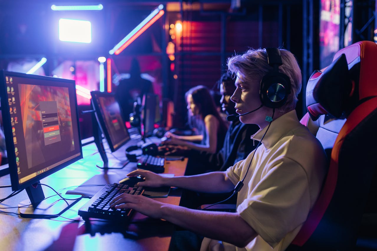 mobile-01 Gamers engaged in a competitive session, equipped with headsets and monitors in an immersive setup.