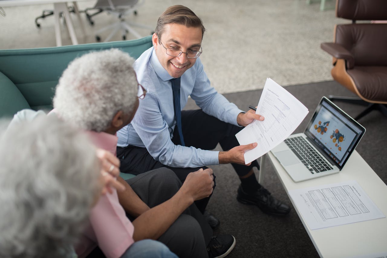 digital Financial advisor discussing documents with senior clients in an office setting, showcasing a collaborative consulting session.